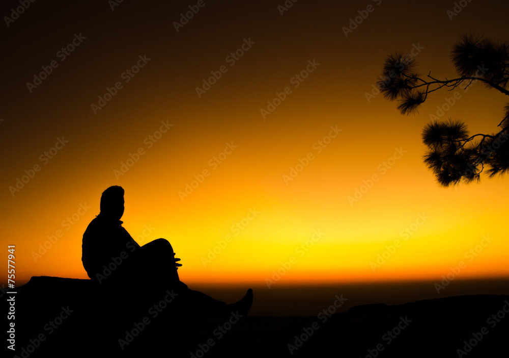 silhouette of man sitting on rock