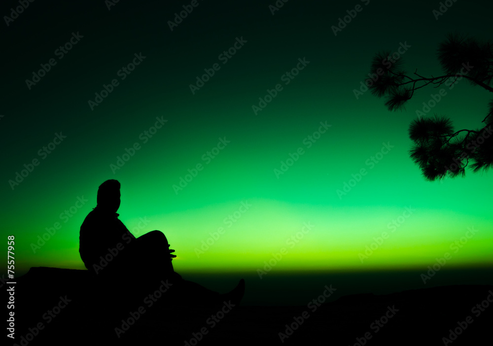 silhouette of man sitting on rock