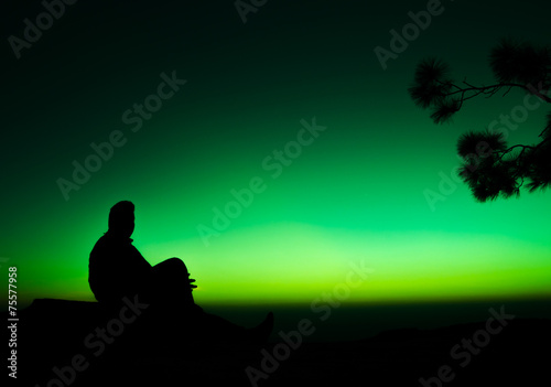 silhouette of man sitting on rock