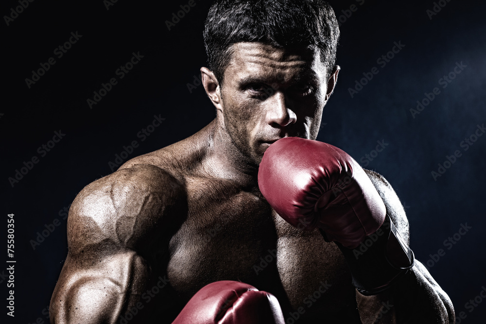 Strong muscular boxer in red boxing gloves. A man in a boxing st