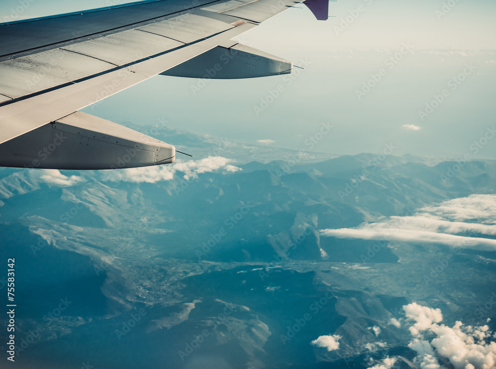 Obraz premium Wing of airplane flying above the clouds