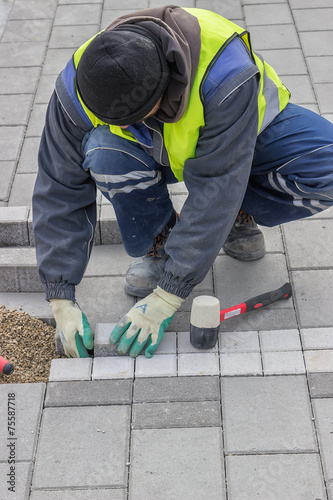 Construction worker installing sidewalk pavement