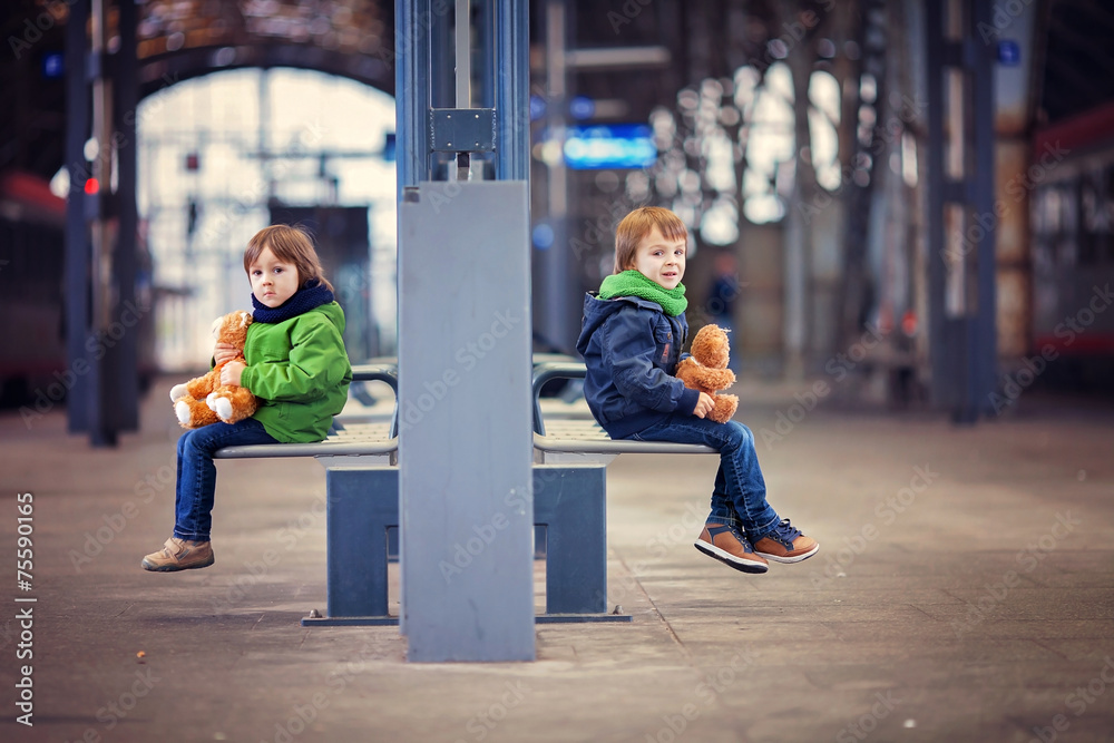Two boys, sitting in a bench on the railway station