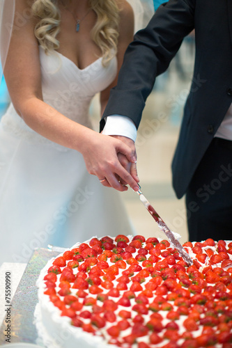 Newlyweds cut the wedding cake with strawberries