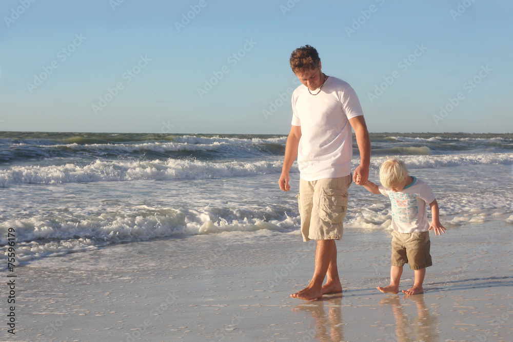 Young Child Holding Father's Hand While Walking in Ocean on Beac Young Child Holding Father's Hand While Walking in Ocean on Beac
