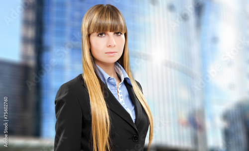 Confident female manager standing in front of glass buildings