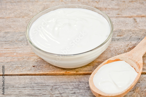 sour cream in a glass bowl and wooden spoon