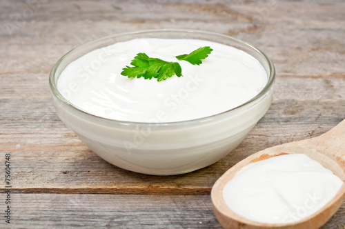 sour cream in a glass bowl and wooden spoon