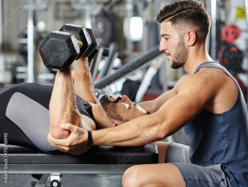 Cuadro en lienzo Personal instructor helping a man in the gym