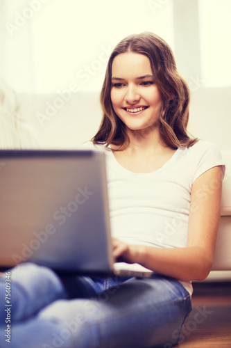 smiling teenage girl with laptop computer at home