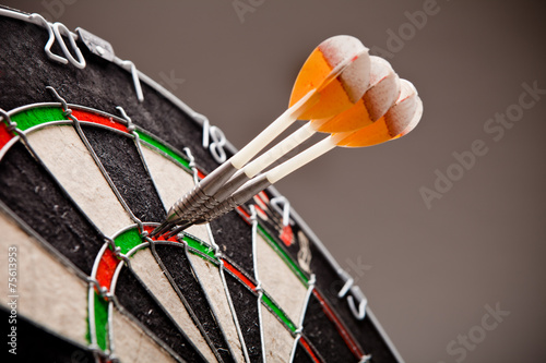 Three darts hitting perfect 180 score on dart board