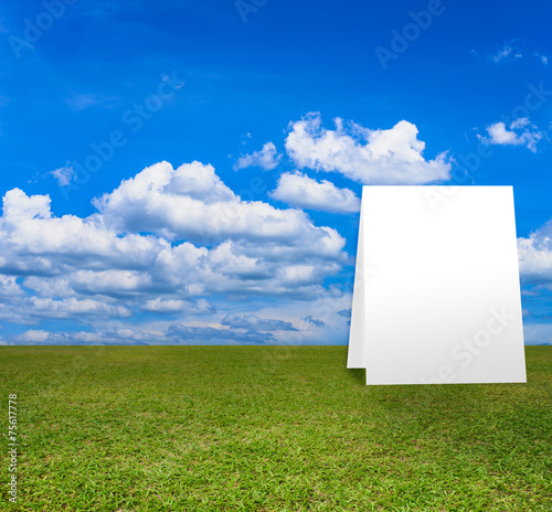 Poster standing on Green field under blue clouds sky