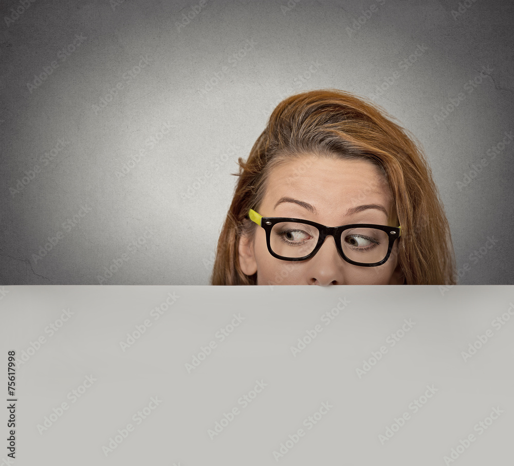 Curious woman peeking over edge of blank empty paper billboard Curious woman peeking over edge of blank empty paper billboard