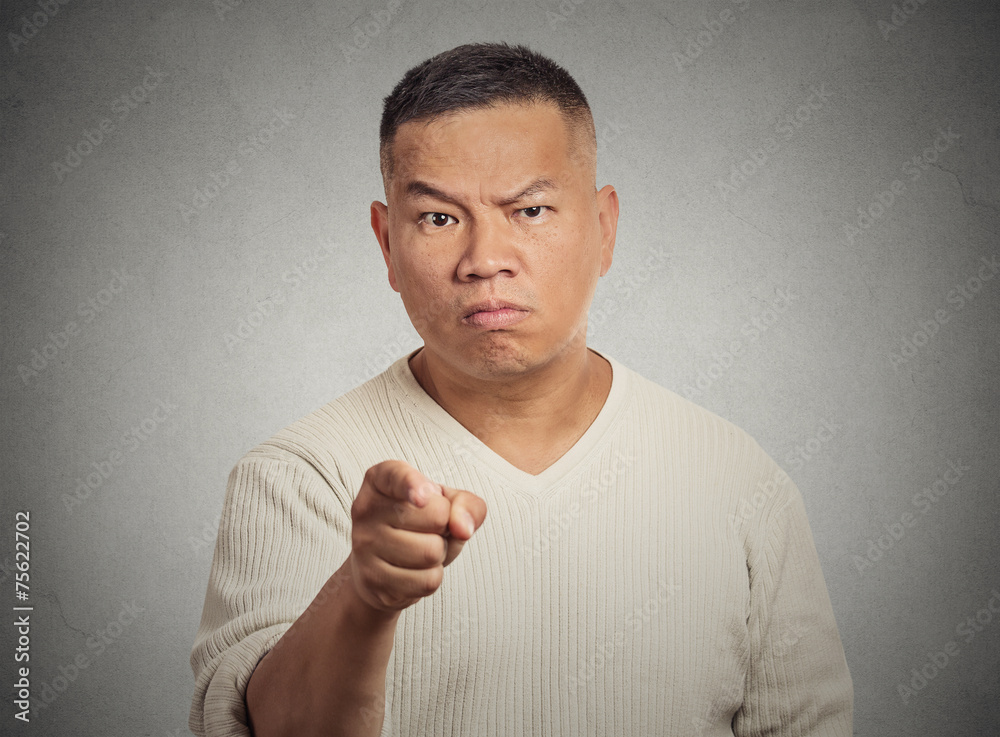 Angry man pointing his finger at somebody grey background Stock Photo
