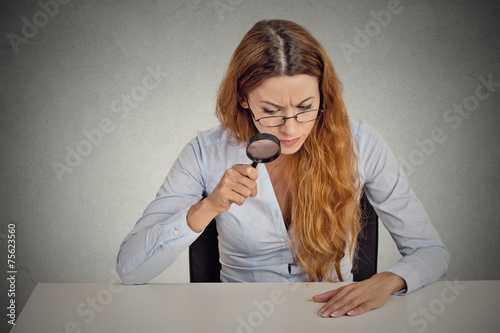 Φωτογραφία Woman skeptically looking through magnifying glass at table