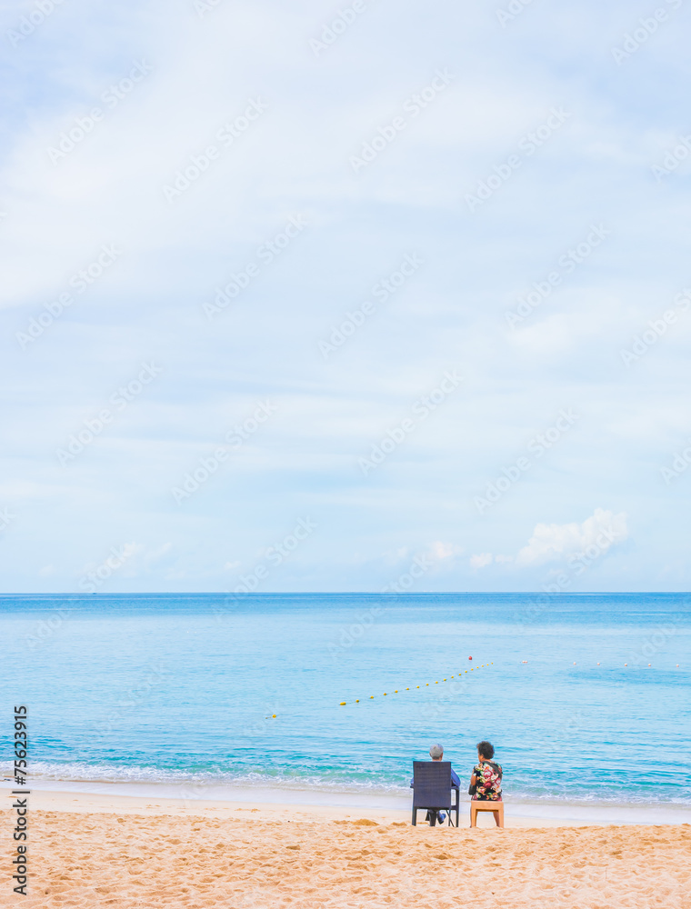 couple sitting on the beach looking on the horizon.