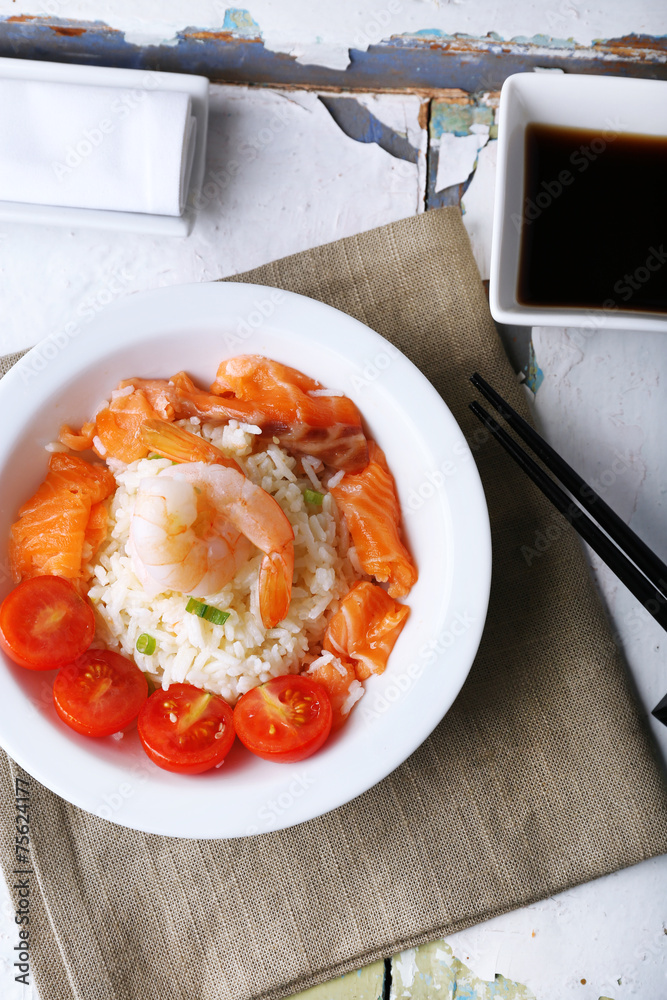 Boiled rice and shrimps, salmon and tomatoes in bowl,