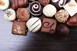Assorted chocolates on the dark wooden smooth background