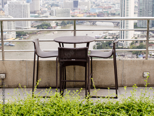 Rattan oone table with two stool chairs standing against the ter photo