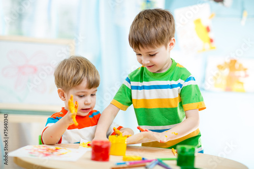 smiling kids play and paint at home or kindergarten or