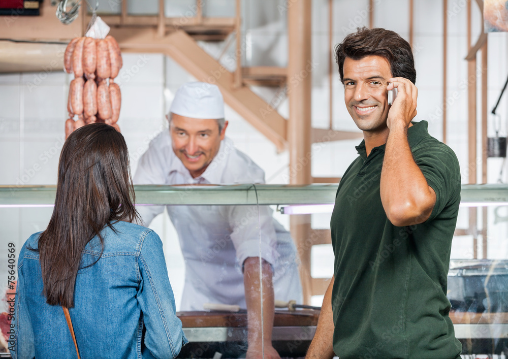 Obraz premium Happy Man On Call While Woman Buying Meat