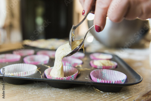 A woman at a kitchen table baking fairy cakes.  photo