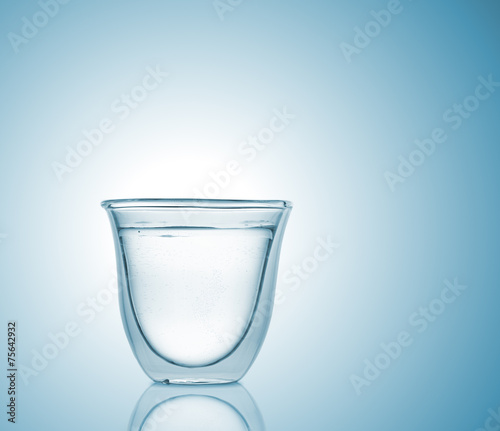 Glass with carbonated water on blue gradient background