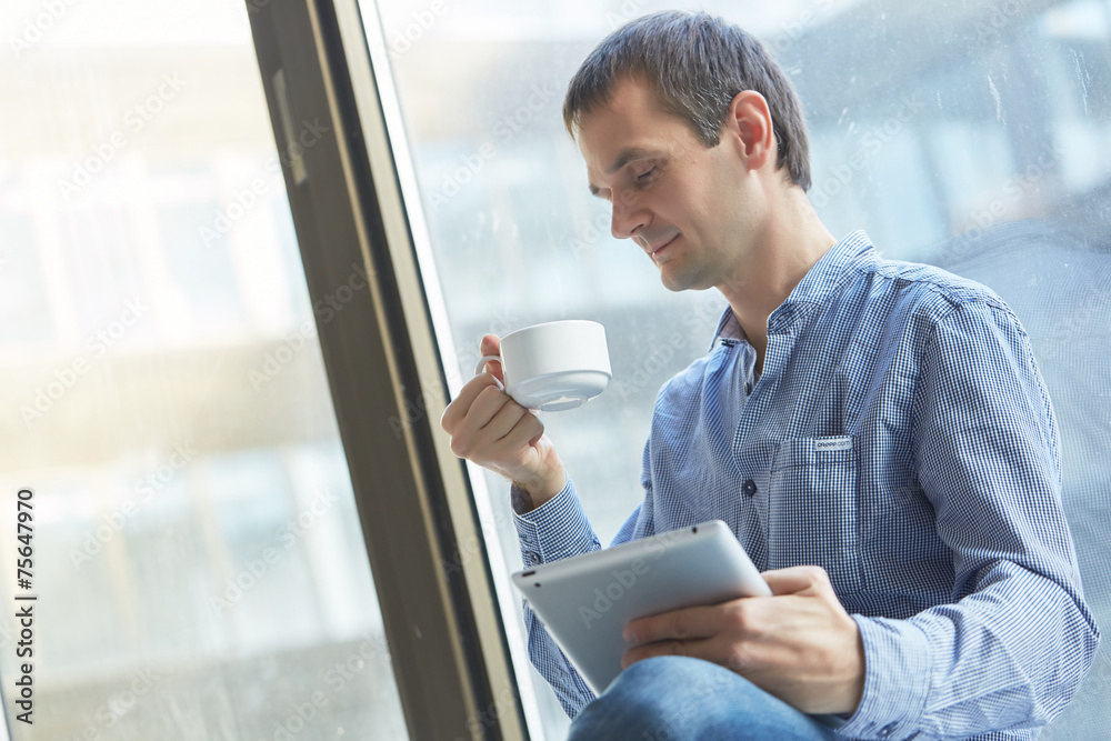 Fototapeta premium businessman with a cup of coffee and with the tablet at the wind