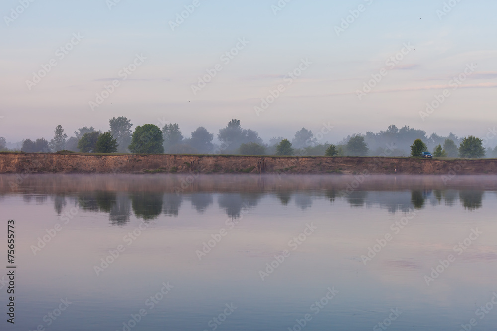 Reflection of trees on the shore at sunrise rays Reflection of trees on the shore at sunrise rays