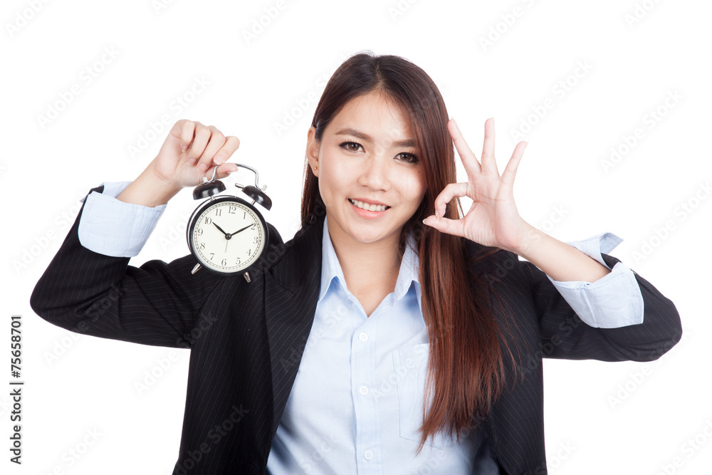 Young Asian businesswoman show OK with alarm clock Young Asian businesswoman show OK with alarm clock