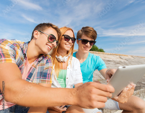 group of smiling friends with tablet pc outdoors © Syda Productions