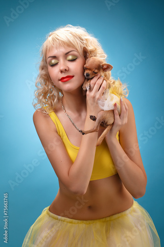 glamorous girl holding a chihuahua dog. Blonde hugging a puppy. 