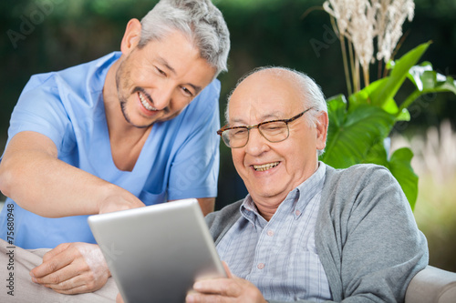 Nurse And Senior Man Enjoying While Using Tablet Computer