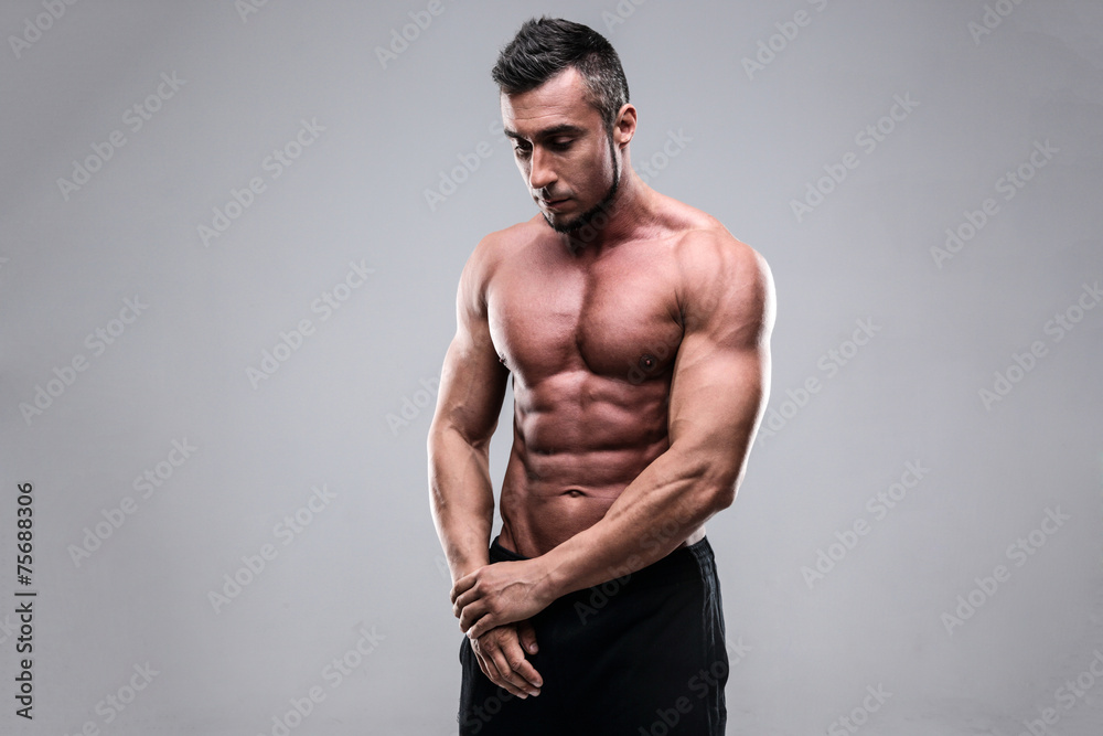 Shirtless man looking downwards over gray background Shirtless man looking downwards over gray background