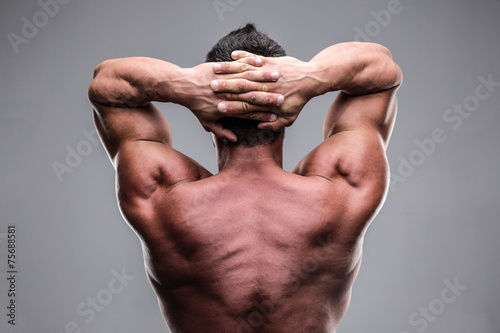 Rear view of a muscular man over gray background