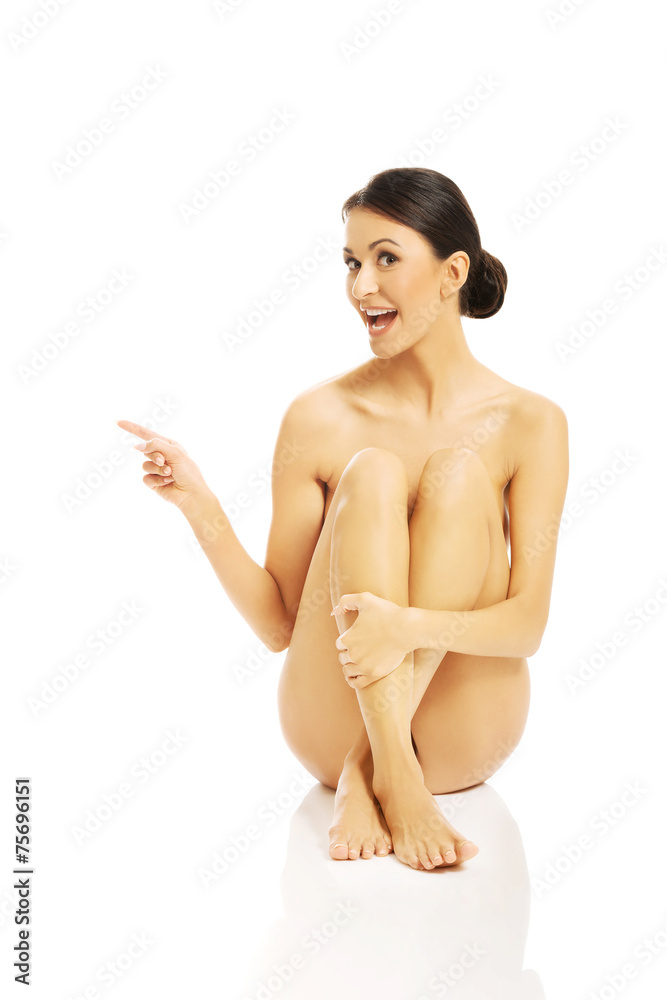 Fototapeta premium Nude woman sitting and pointing to the left