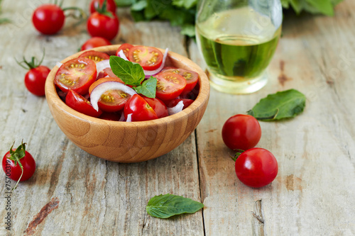 Cherry tomato salad with onion and basil leaves
