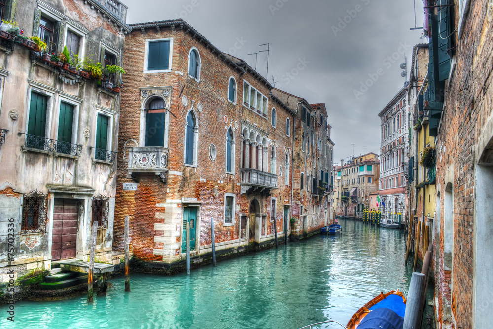 Narrow canal in Venice under a gray sky