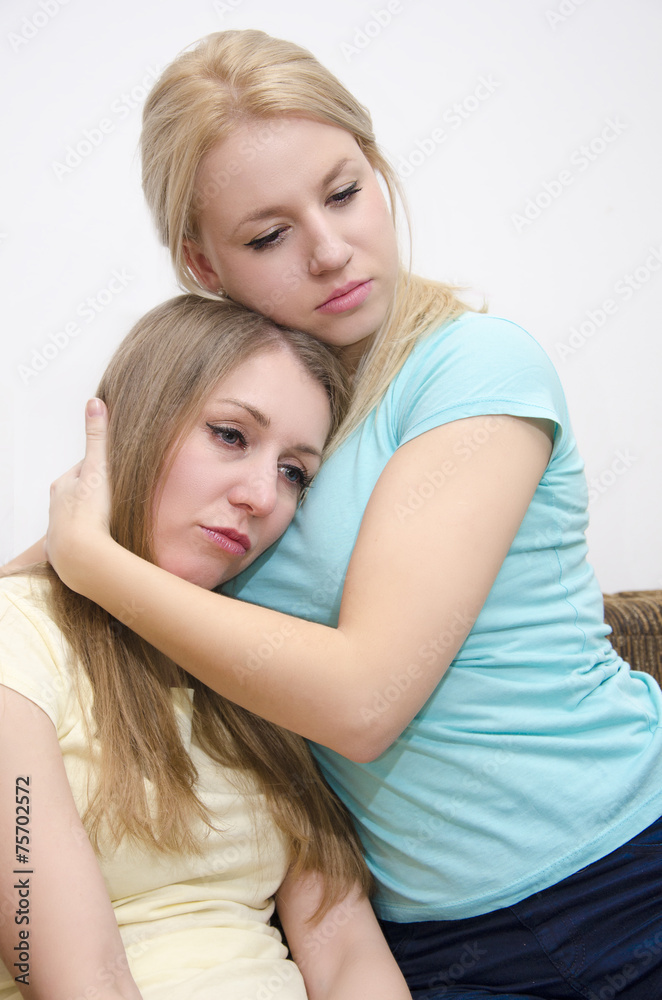 Pretty young girl comforting her friend, holding her in her arms