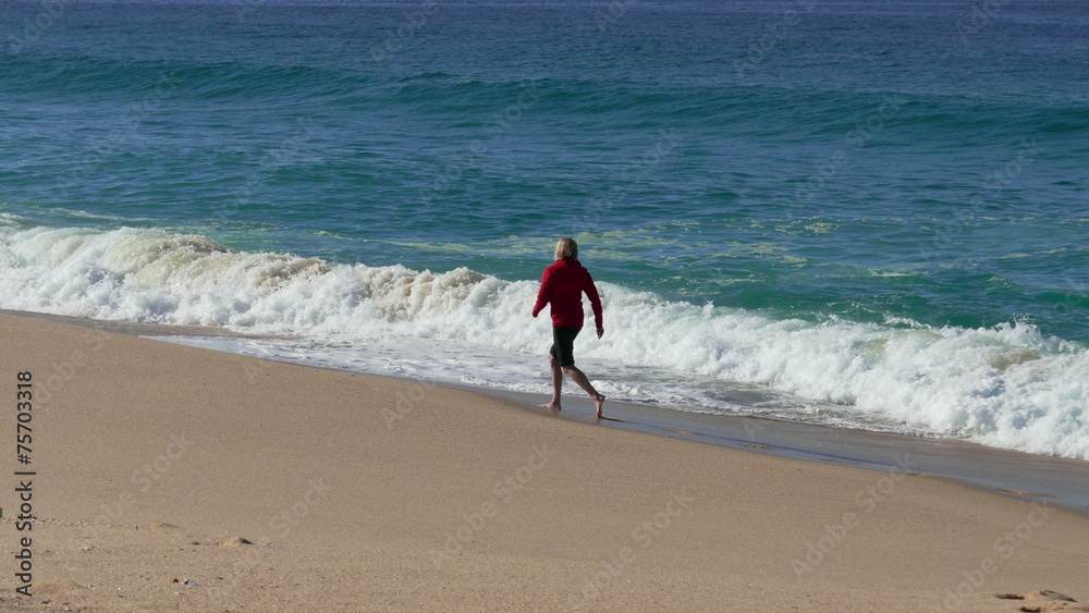 Woman Running on Beach with Waves in the Background Woman Running on Beach with Waves in the Background
