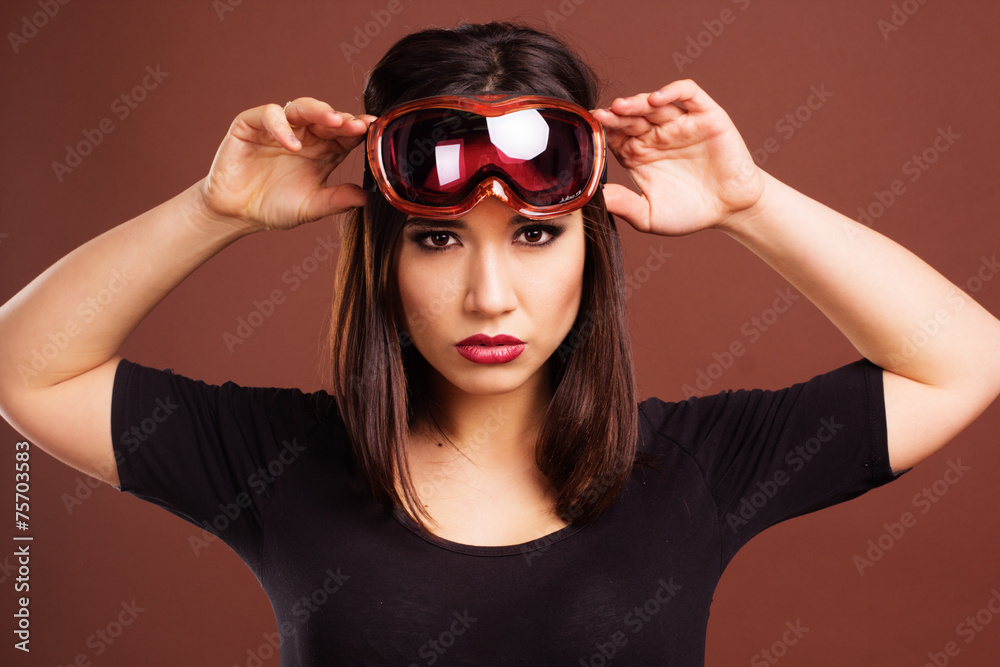 Woman with ski goggles isolated on brown Woman with ski goggles isolated on brown