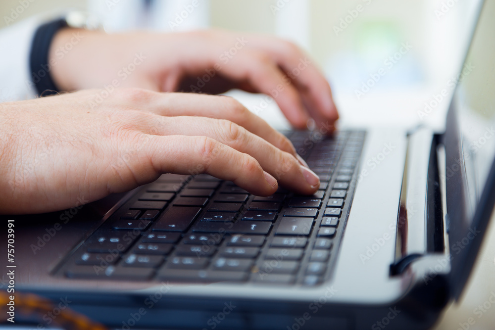 Young handsome man working in his office with laptop.