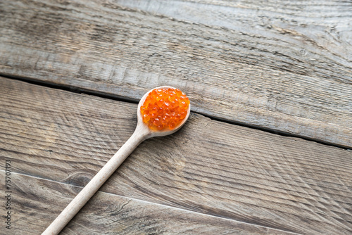 Scoop of red caviar on the wooden background