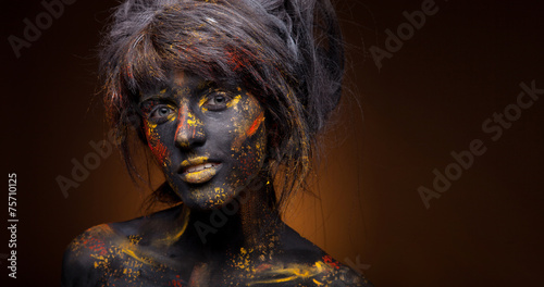 dark portrait of woman in black paint with yellow smudges