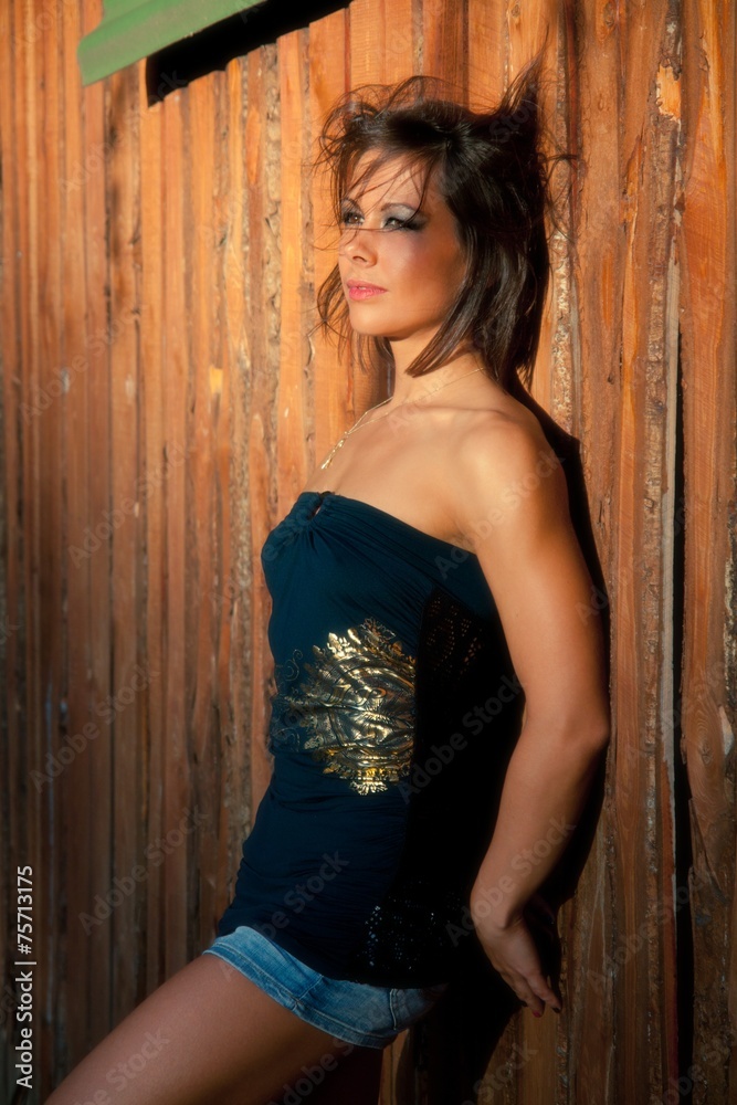 Fototapeta premium Young woman portrait near the wall in sunshine