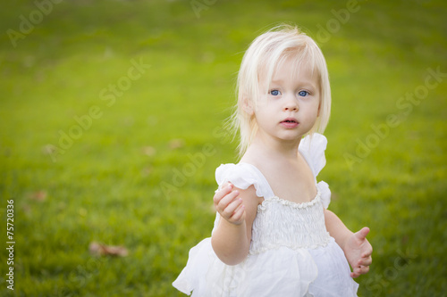 Adorable Little Girl Wearing White Dress In A Grass Field