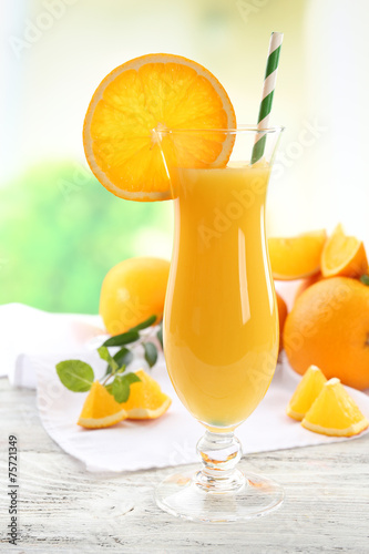 Glass of orange juice with straw and slices
