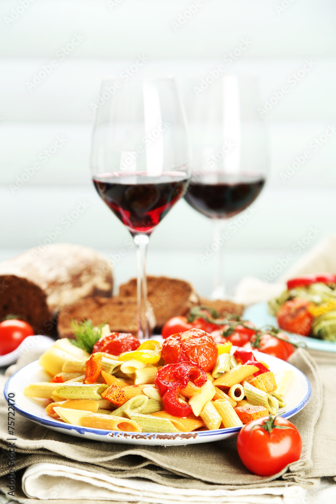Pasta salad with vegetables and two glasses of red wine