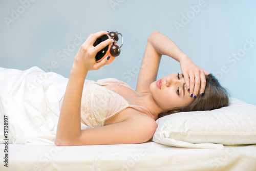 Canvas-taulu beauty lying on the bed with a clock