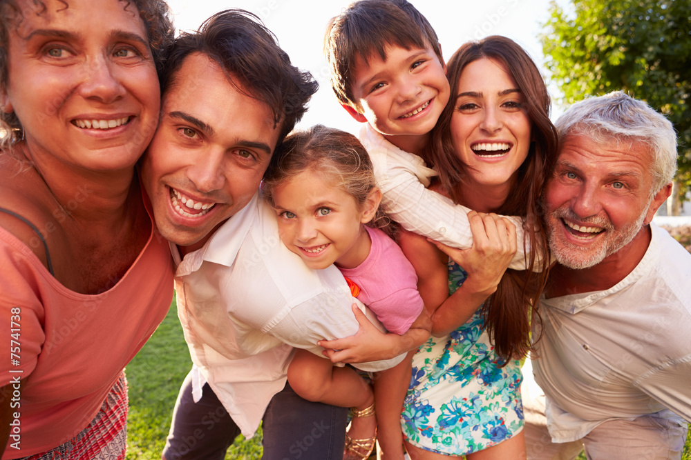 Multi Generation Family Giving Children Piggybacks In Park Multi Generation Family Giving Children Piggybacks In Park
